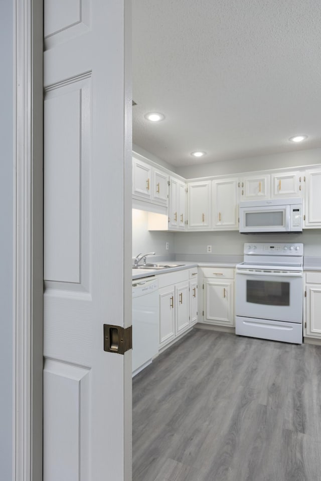 kitchen featuring sink, white appliances, light hardwood / wood-style flooring, and white cabinets