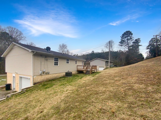 exterior space featuring a garage, central AC, a deck, and a lawn