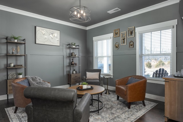 sitting room with dark wood-type flooring, a wealth of natural light, crown molding, and an inviting chandelier