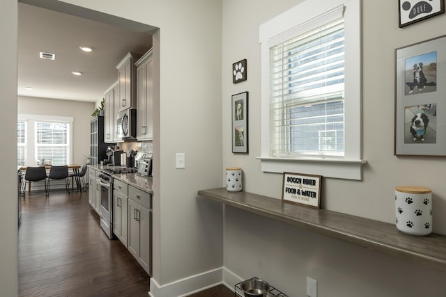 kitchen featuring backsplash, appliances with stainless steel finishes, dark hardwood / wood-style floors, and dark stone countertops