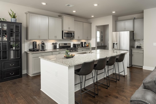 kitchen featuring sink, an island with sink, gray cabinetry, and appliances with stainless steel finishes