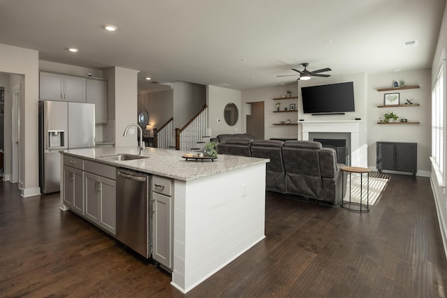 kitchen with sink, appliances with stainless steel finishes, gray cabinets, and an island with sink