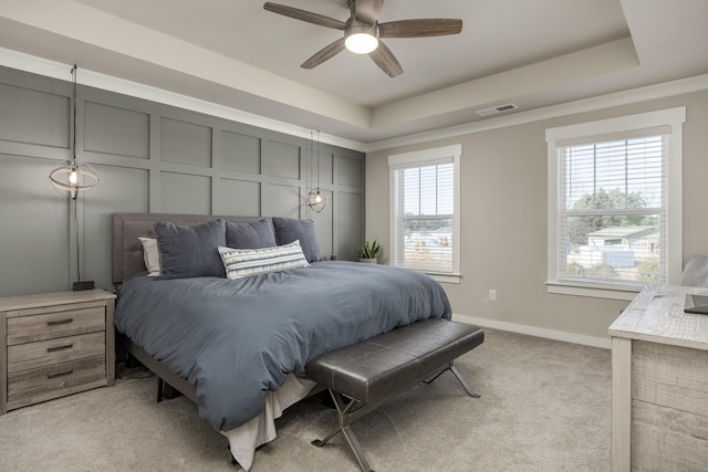 carpeted bedroom featuring ceiling fan and a tray ceiling