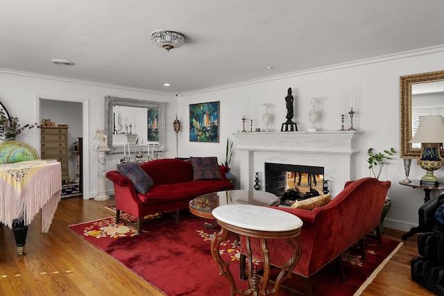 living room with crown molding, wood-type flooring, and a fireplace