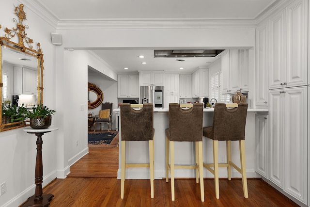 kitchen featuring a breakfast bar area, white cabinets, crown molding, dark hardwood / wood-style flooring, and stainless steel refrigerator with ice dispenser