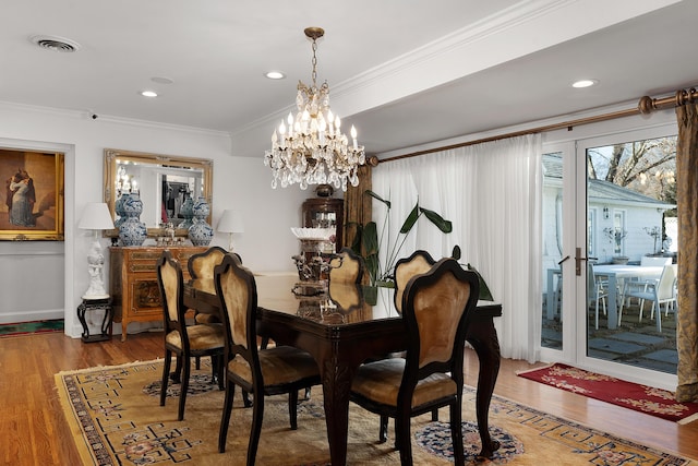 dining area featuring crown molding, wood-type flooring, and an inviting chandelier