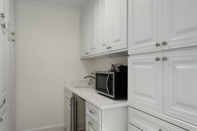 kitchen featuring white cabinetry, crown molding, and sink