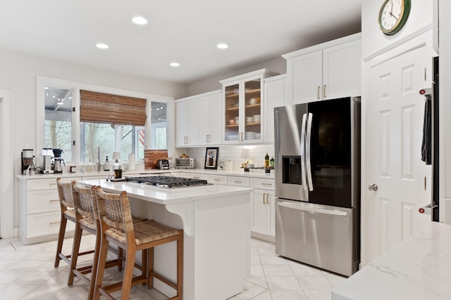 kitchen with white cabinetry, light stone countertops, appliances with stainless steel finishes, and a center island