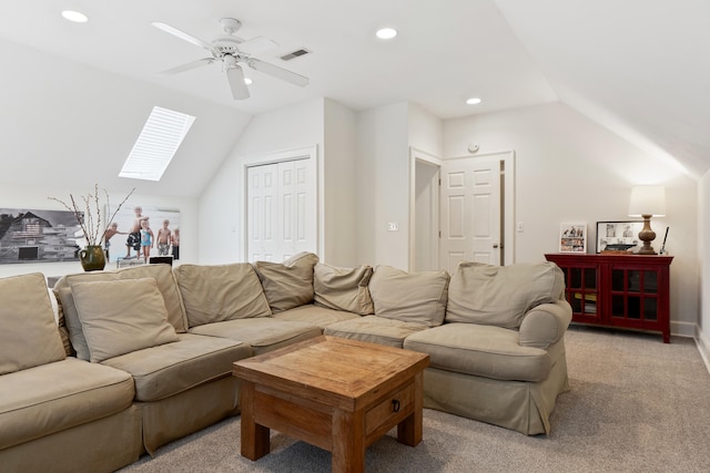 living room with ceiling fan, light colored carpet, and vaulted ceiling with skylight