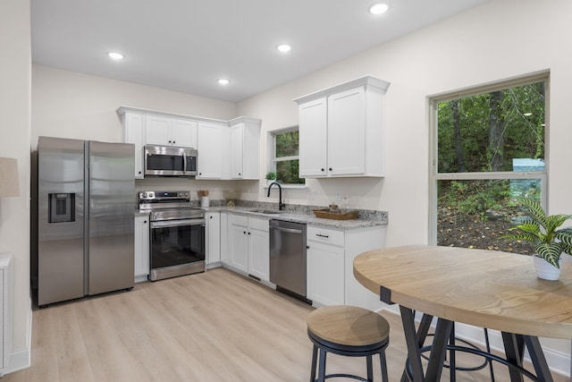 kitchen featuring sink, white cabinetry, light stone countertops, and stainless steel appliances