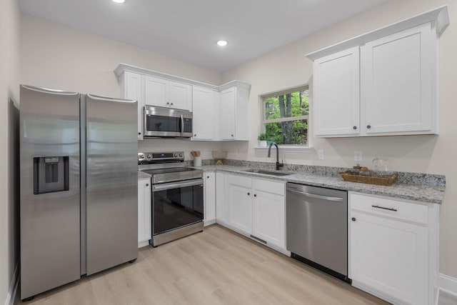 kitchen featuring sink, light stone counters, white cabinets, and stainless steel appliances