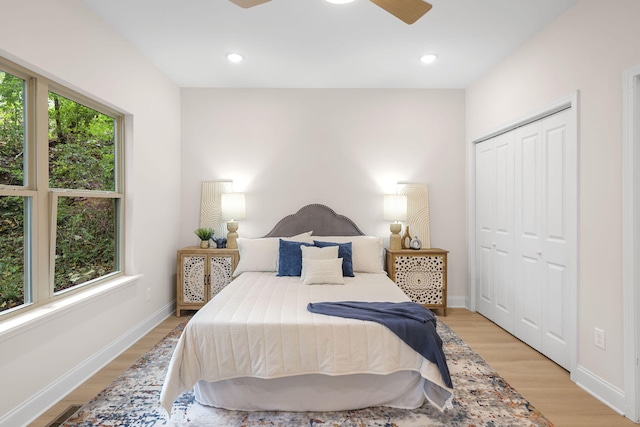 bedroom with ceiling fan, light hardwood / wood-style floors, multiple windows, and a closet