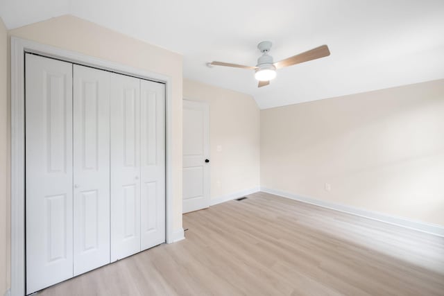 unfurnished bedroom featuring ceiling fan, a closet, lofted ceiling, and light hardwood / wood-style flooring