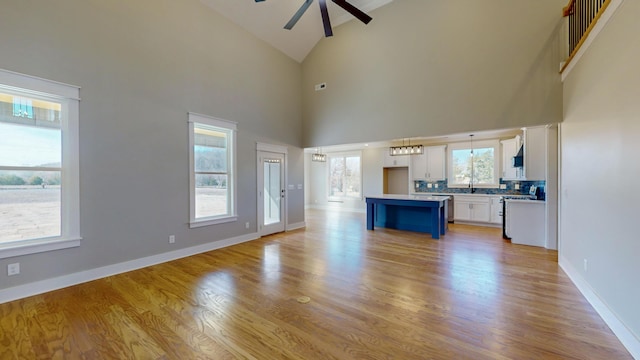 unfurnished living room with ceiling fan, high vaulted ceiling, and light hardwood / wood-style floors