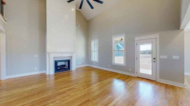 unfurnished living room with ceiling fan, high vaulted ceiling, a premium fireplace, and light hardwood / wood-style floors