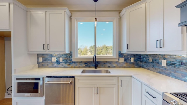 kitchen featuring appliances with stainless steel finishes, light stone countertops, sink, and white cabinets