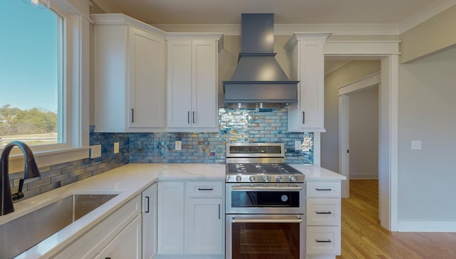 kitchen featuring sink, white cabinets, range with two ovens, light stone counters, and custom range hood