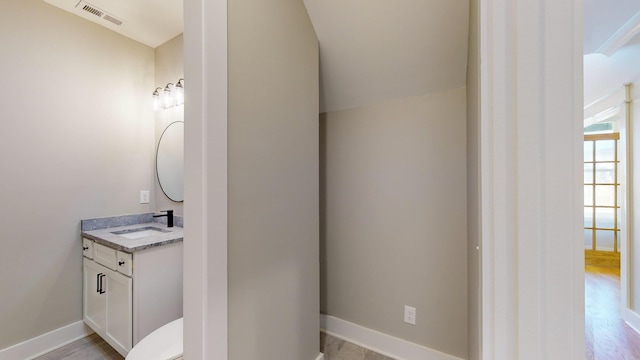 bathroom with hardwood / wood-style flooring, vanity, and lofted ceiling