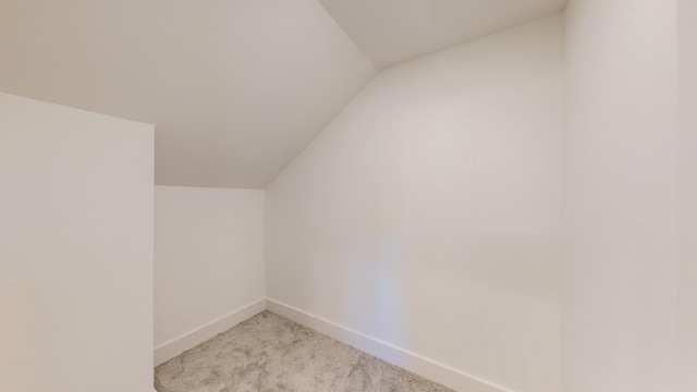 additional living space with vaulted ceiling and light carpet