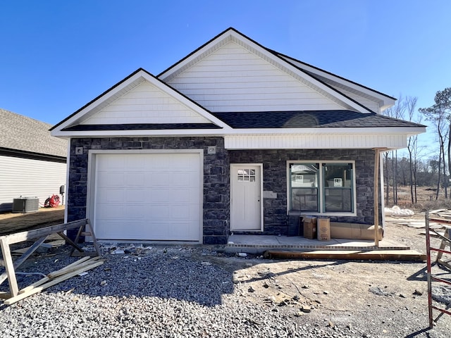 view of front of property featuring covered porch, cooling unit, and a garage