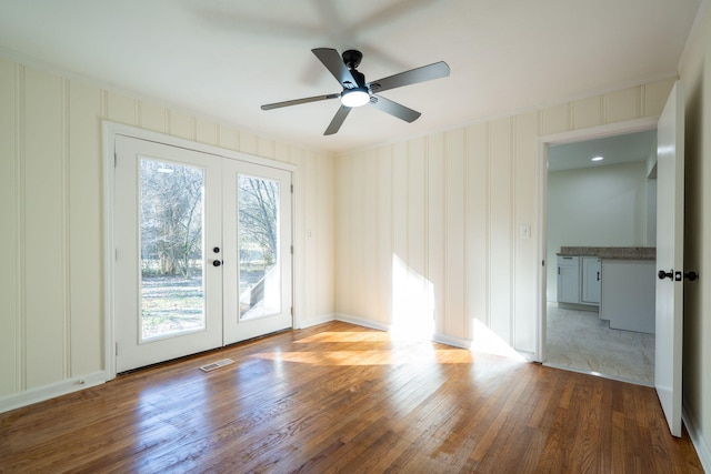 empty room with french doors, ceiling fan, and light hardwood / wood-style floors