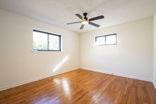 empty room featuring hardwood / wood-style flooring, ceiling fan, plenty of natural light, and a textured ceiling