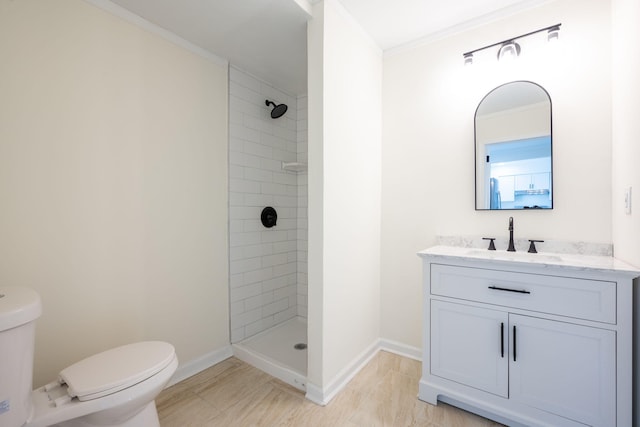 bathroom featuring ornamental molding, a tile shower, vanity, and toilet