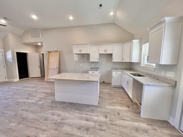 kitchen with white cabinetry, visible vents, a center island, and lofted ceiling