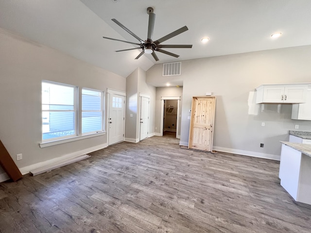 unfurnished living room with wood finished floors, vaulted ceiling, baseboards, visible vents, and a ceiling fan