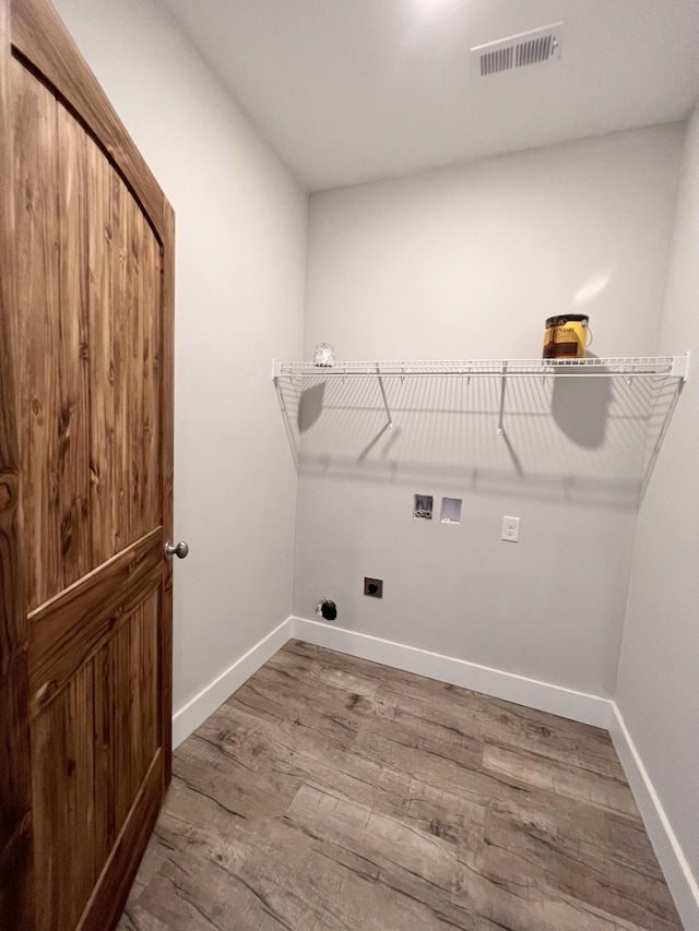clothes washing area with visible vents, baseboards, hookup for a washing machine, wood finished floors, and laundry area