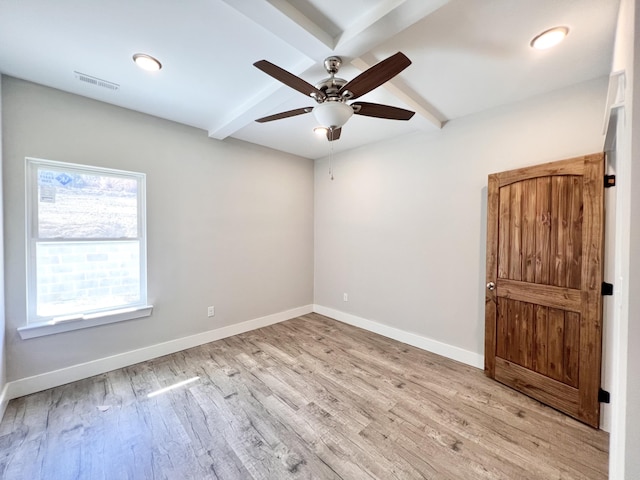 empty room with wood finished floors, beamed ceiling, ceiling fan, baseboards, and visible vents