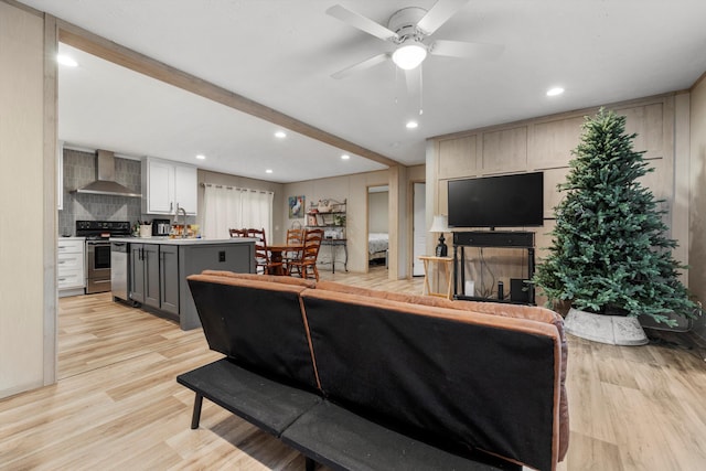 living room with beam ceiling, ceiling fan, and light hardwood / wood-style floors