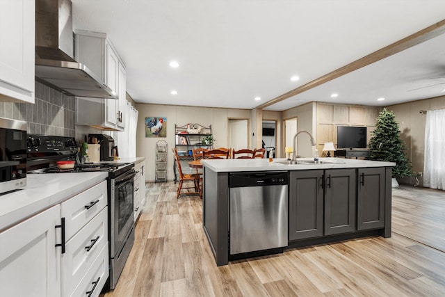 kitchen featuring sink, white cabinets, stainless steel appliances, a center island with sink, and wall chimney exhaust hood