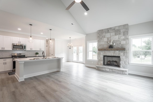 kitchen featuring a kitchen island with sink, pendant lighting, white cabinets, and appliances with stainless steel finishes