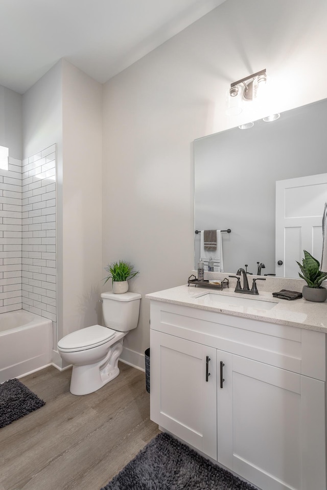 full bathroom featuring hardwood / wood-style flooring, tiled shower / bath, vanity, and toilet