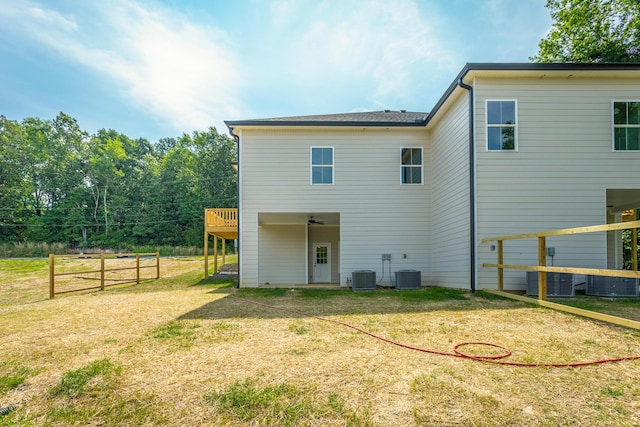 rear view of property with a wooden deck, a lawn, and central air condition unit