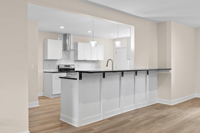 kitchen with pendant lighting, white cabinets, decorative backsplash, wall chimney exhaust hood, and stainless steel electric range