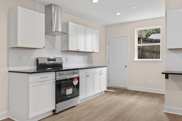 kitchen with electric stove, white cabinetry, light hardwood / wood-style floors, and wall chimney range hood