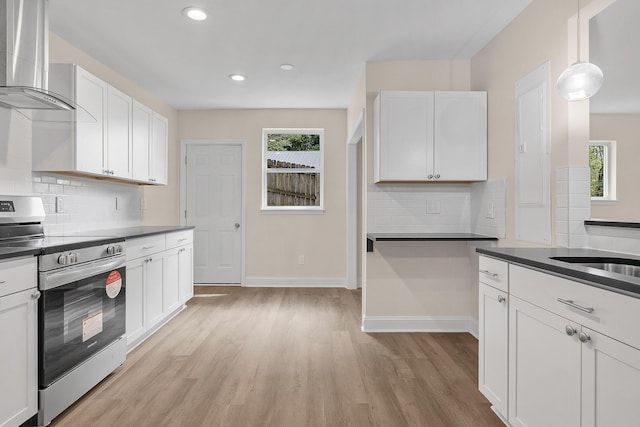 kitchen with tasteful backsplash, white cabinets, electric range, and wall chimney exhaust hood