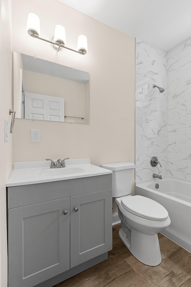 full bathroom featuring hardwood / wood-style flooring, tiled shower / bath, vanity, and toilet