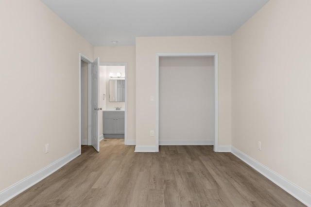 unfurnished bedroom with connected bathroom and light hardwood / wood-style flooring