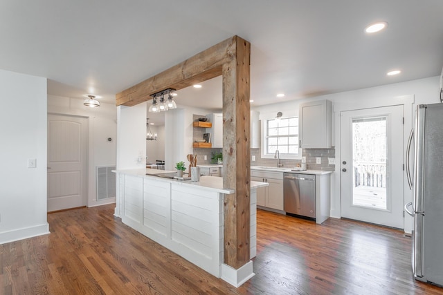 kitchen with sink, dark wood-type flooring, appliances with stainless steel finishes, white cabinetry, and decorative backsplash