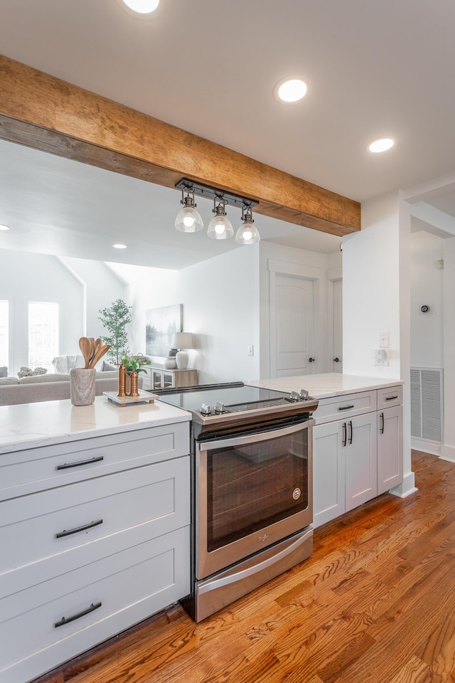 kitchen featuring beamed ceiling, white cabinetry, light wood-type flooring, and electric range