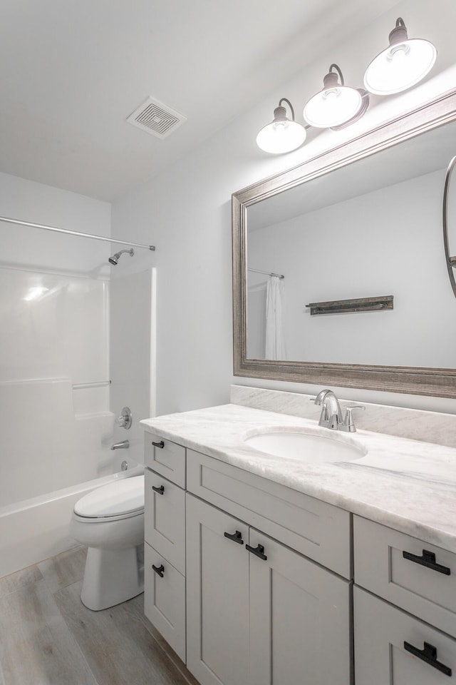 full bathroom featuring hardwood / wood-style flooring, shower / tub combination, vanity, and toilet