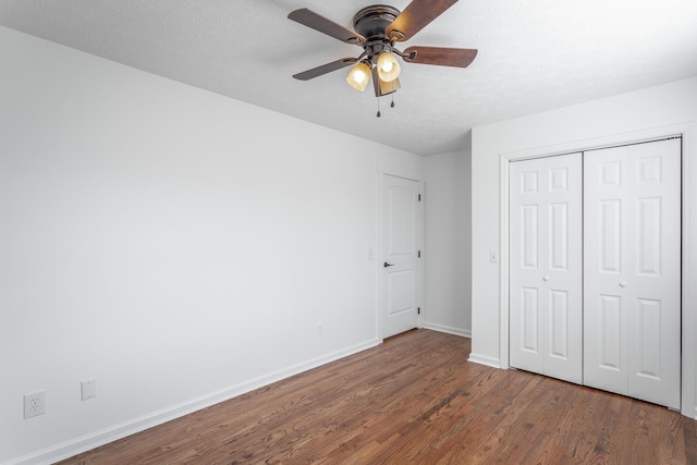 unfurnished bedroom with dark wood-type flooring, a closet, ceiling fan, and a textured ceiling