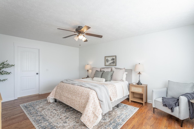 bedroom featuring ceiling fan, hardwood / wood-style flooring, and a textured ceiling