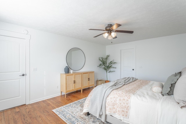 bedroom featuring hardwood / wood-style flooring, ceiling fan, and a textured ceiling