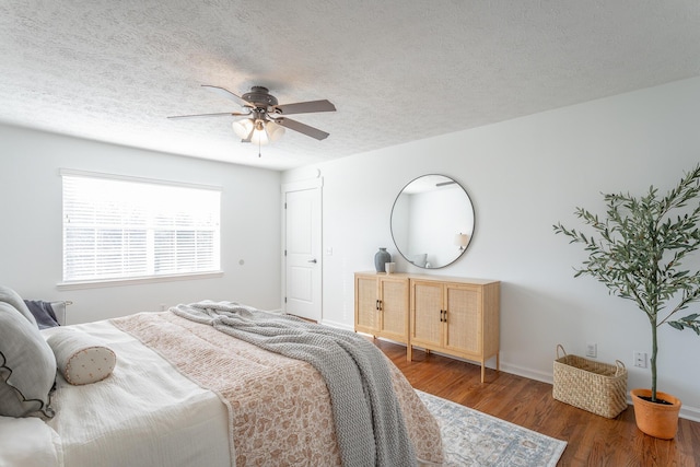 bedroom with ceiling fan, dark hardwood / wood-style flooring, and a textured ceiling