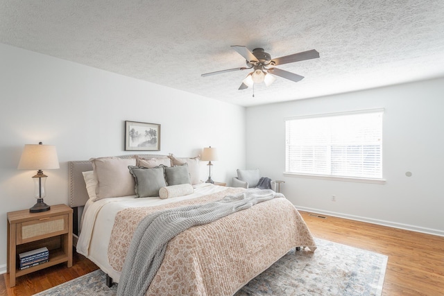 bedroom featuring hardwood / wood-style flooring, ceiling fan, and a textured ceiling