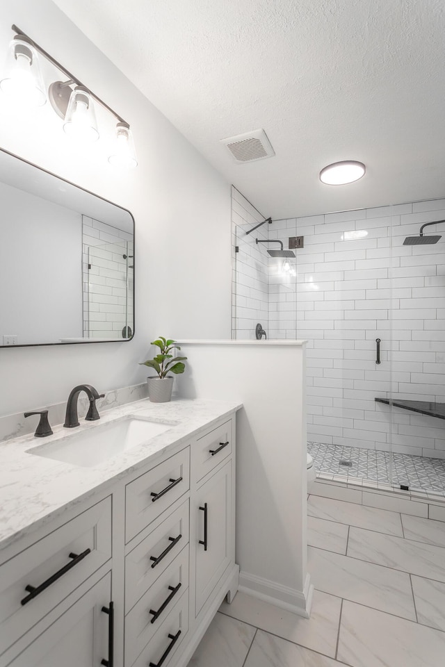 bathroom with vanity, toilet, a textured ceiling, and a shower with shower door